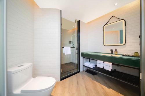 a bathroom with a toilet and a sink and a mirror at Premier City Comfort Hotel Wuhan Yellow Crane Shouyi Road Metro Station in Wuhan