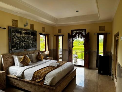 a bedroom with a large bed and a balcony at Puri Prana Guest House in Ubud