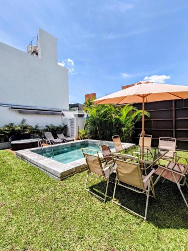 a backyard with a pool and chairs and an umbrella at Private house with two pools for up to 25 people in Atlacholoaya