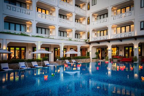 a hotel swimming pool with chairs and umbrellas at RiverTown Hoi An Resort & Spa in Hoi An