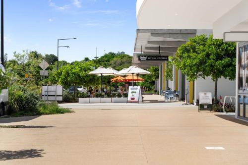 a building with tables and umbrellas in a courtyard at Wurtulla Seabreeze Sanctuary - Pool Spa & PF in Kawana Waters
