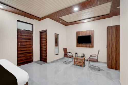 a living room with two chairs and a tv at Hotel O THE GOMTI GLITZ in Gomti Nagar