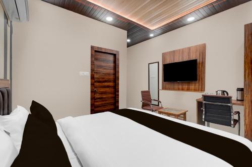 a bedroom with a bed and a flat screen tv at Hotel O THE GOMTI GLITZ in Gomti Nagar