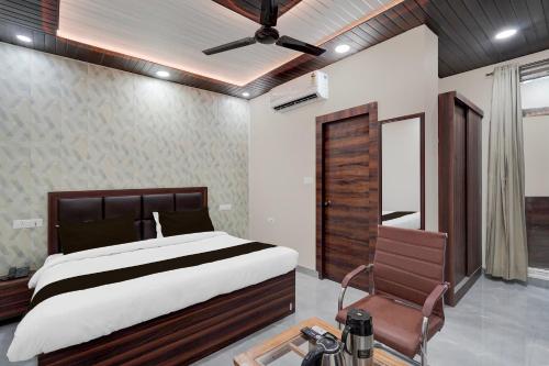 a bedroom with a large bed and a chair at Hotel O THE GOMTI GLITZ in Gomti Nagar