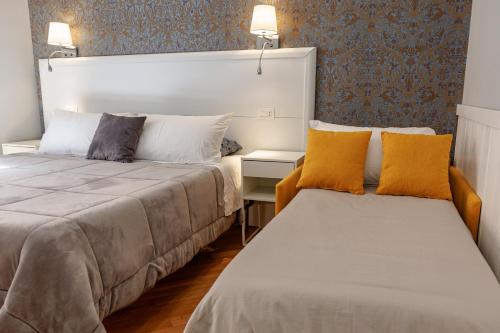 ローマにあるベッド アンド ベストの黄色い枕が置かれたホテルの部屋にはベッドが2つある