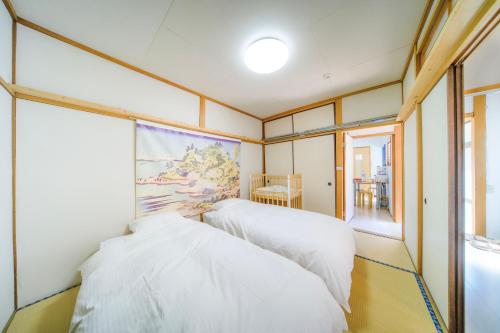 two white beds in a room with a window at INARI guest house 栗林公園徒歩3分 二棟貸切 駐車場一台無料 in Takamatsu