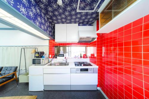 a kitchen with red tiles on the walls at INARI guest house 栗林公園徒歩3分 二棟貸切 駐車場一台無料 in Takamatsu