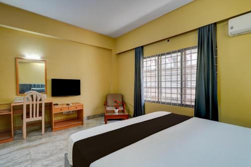 a bedroom with a bed and a desk and a television at Hotel O ALT pods in Bengaluru