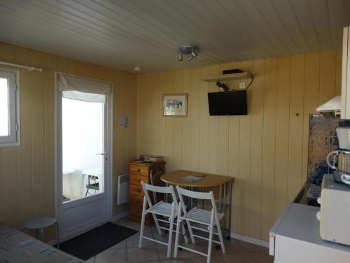 une petite cuisine avec une table et deux chaises dans l'établissement Résidence Fleur des Pins - Gites & Chambres d'Hôtes, à Saint-Georges-dʼOléron