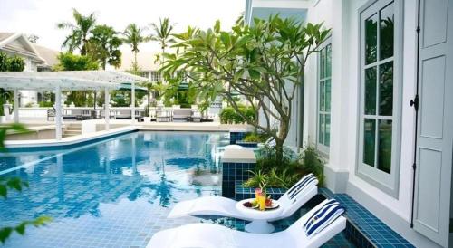 a swimming pool with two white chairs next to it at My BanLao Hotel in Luang Prabang