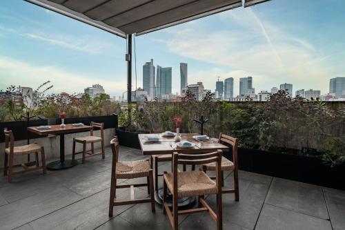 a patio with tables and chairs and a view of the city at Hotel Casa Izel Roma Norte in Mexico City