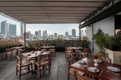 a restaurant with tables and chairs and a view of the city at Hotel Casa Izel Roma Norte in Mexico City