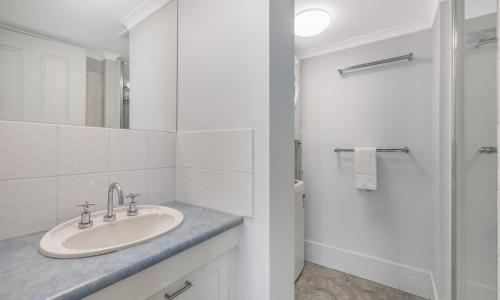 a white bathroom with a sink and a shower at Sunny Coast Escapes - Maroochydore in Maroochydore