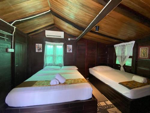 two beds in a small room with wooden walls at Cenanghill Beachfront in Pantai Cenang