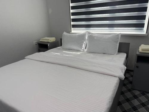 a bedroom with a bed with white sheets and pillows at SILVER HOTEL navoiy in Navoi