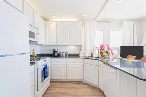 a white kitchen with white cabinets and appliances at The Cayucan Bungalows by AvantStay Pet-Friendly Getaway Steps from Cayucos State Beach in Cayucos