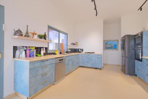 a large kitchen with blue cabinets and a refrigerator at אלגריה - ווילה מהממת עם 4 חדרי שינה ונוף משגע בכמון in Kammon