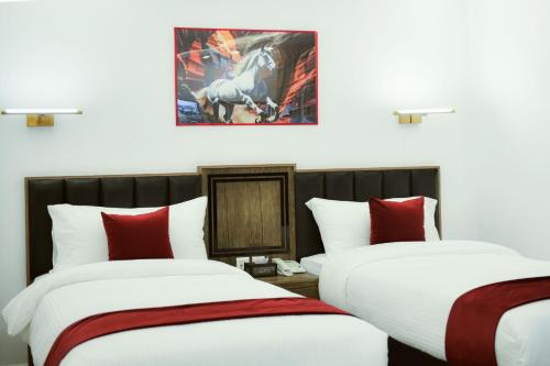two beds in a room with a picture of a horse on the wall at Petra Bermudez Hotel in Wadi Musa
