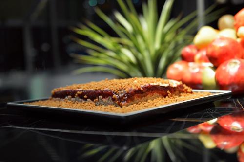 a piece of cake on a plate on a table with apples at Petra Bermudez Hotel in Wadi Musa