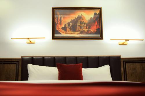 a bedroom with two lamps on the wall and a bed at Petra Bermudez Hotel in Wadi Musa
