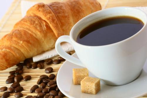 a cup of coffee and a croissant and coffee beans at MyContinental Suceava in Suceava