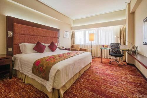 a hotel room with a large bed and a desk at Dalian Grand Continent International Hotel in Dalian