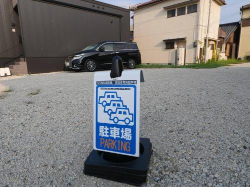 a parking sign in a driveway with a car in the background at TOTONOU Awajishima in Awaji