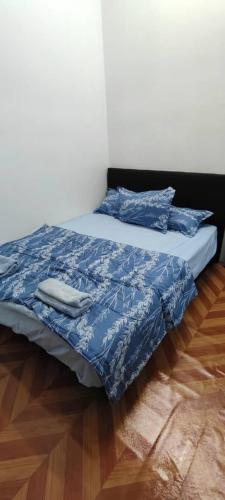 a bed with a blue comforter and pillows on it at Homestay Kg Razali in Kuantan