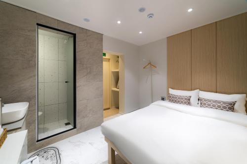 a bedroom with a large white bed and a bathroom at The Central Hongdae in Seoul