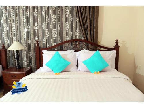 a bedroom with a bed with green and white pillows at PLUM Dreamscape Inan Malang in Rampal