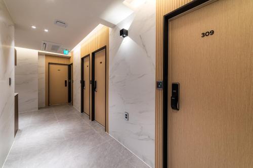 a hallway with a row of doors with marble walls at The Central Hongdae in Seoul