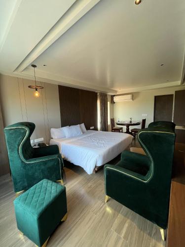 a hotel room with a bed and two green chairs at Hotel Dusk and Dawn in Rāmeswaram