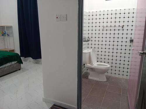 a bathroom with a toilet and a tiled floor at MUSYRIF HOMEstay in Kampong Gong Badak