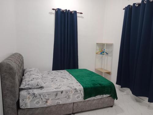 a bedroom with a bed with blue curtains at MUSYRIF HOMEstay in Kampong Gong Badak