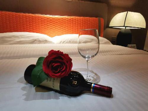 a bottle of wine and a glass and a rose on a bed at Beijing Xixi Friendship Hotel nearby Xidan Shopping Street, Tian'An Men Square, Forbidden City, Houhai & Jingshan Park in Beijing