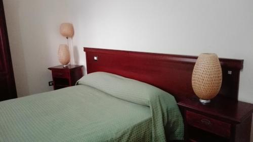 a bedroom with a green bed with two night stands and two lamps at Agriturismo Valle dell'Etna in Roccella Valdemone