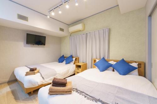 two beds in a room with blue pillows at 栄エリア徒歩圏の好立地 栄まで1駅 名古屋駅まで乗換不要 地下鉄最寄り駅徒歩9分 最大5名 in Nagoya