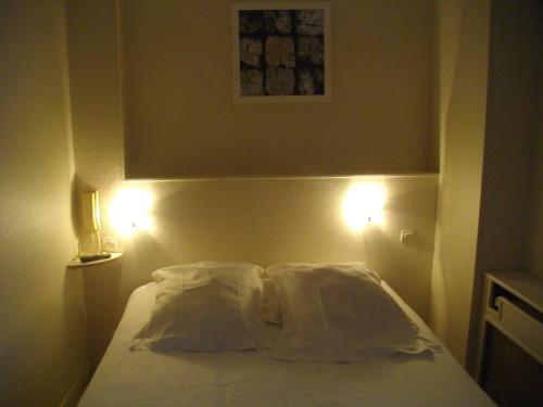 a bedroom with a bed with two pillows and two lights at Hôtel Pacific in Calais