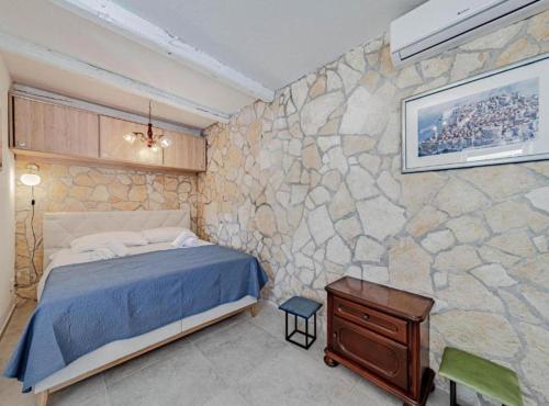 a bedroom with a stone wall with a bed at Natur Olive House Ston in Ston