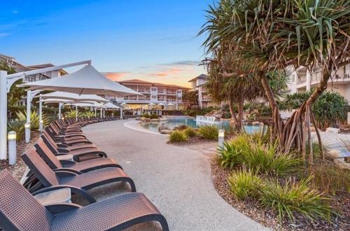 a row of brown chairs sitting next to a resort at The Pool Resort Kingscliff - Private Apartments by Holiday Management Company in Kingscliff
