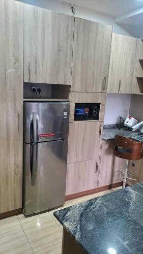 a kitchen with a stainless steel refrigerator and wooden cabinets at Abuja luxury apartment in Abuja