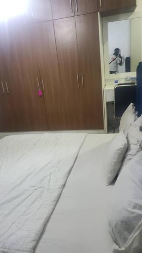 a bedroom with a white bed and wooden cabinets at Abuja luxury apartment in Abuja