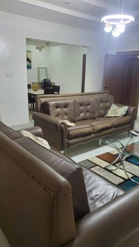 a living room with brown leather couches and a table at Abuja luxury apartment in Abuja
