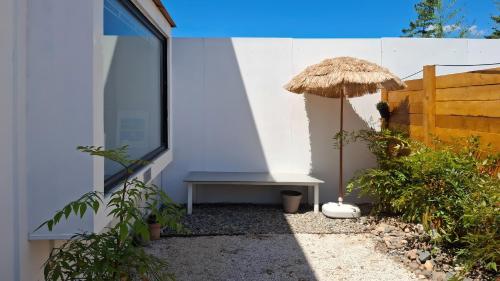 a bench with a straw umbrella next to a building at gyeongju planb pet pension in Gyeongju