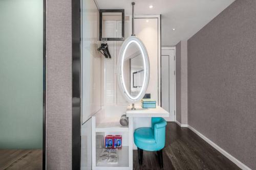 a bathroom with a mirror and a blue stool at Xana Hotelle Chongqing Jiefangbei Center Branch in Chongqing