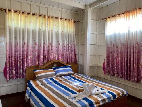 een slaapkamer met een bed en roze gordijnen bij Khun Cham-nan Herb Garden House in Phichai