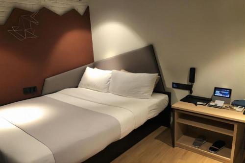 a bedroom with a bed and a desk with a laptop at YUNIK-Shanghai Zhongshan Park Yan'an Xi Road in Shanghai