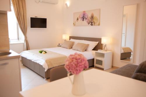 a bedroom with a bed and a vase of flowers on a table at Summer Lounge Apartments in Split