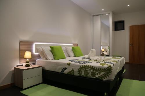 a bedroom with a large bed with green pillows at A&M House in Arco da Calheta