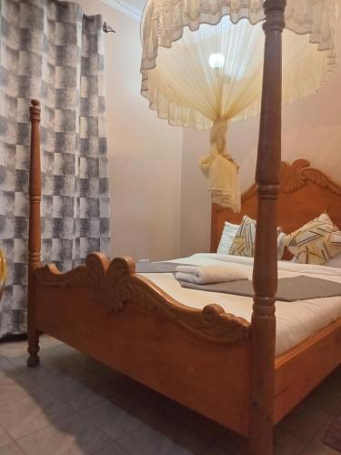 a bedroom with a wooden bed with a canopyved bed sidx sidx at Villa Serene Hotel Kitale in Kitale